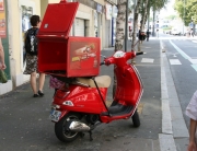 A red scooter with a box on the back of it.
