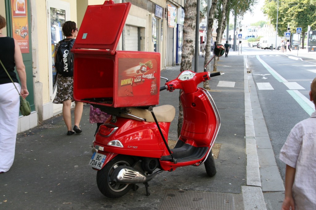 A red scooter with a box on the back of it.
