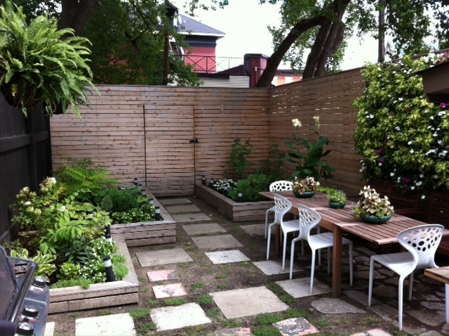 A patio with a table and chairs, plants and a fence.