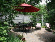 A patio with an umbrella and chairs on the side.