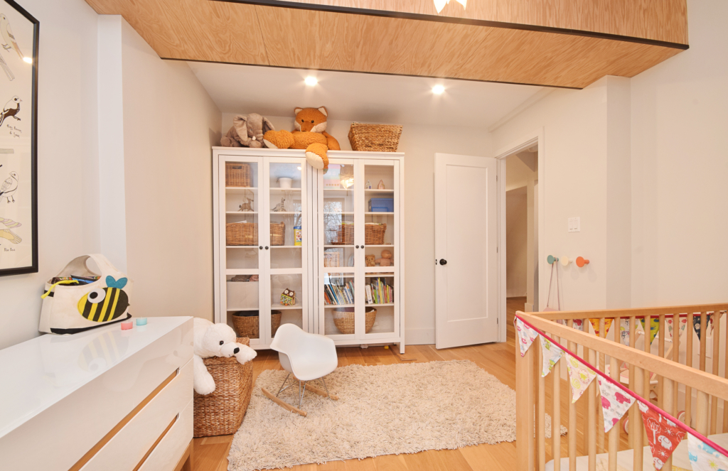 A baby room with white furniture and wooden floors