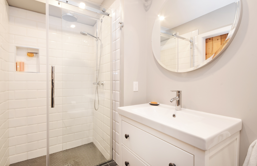 A bathroom with white tile and a walk in shower.