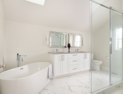 A bathroom with white cabinets and a large tub.