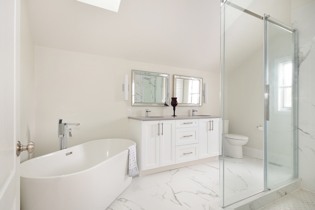 A bathroom with white cabinets and a large tub.