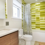 A bathroom with green tiles and white walls.