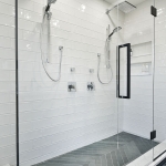 A large white tiled shower with black and gray tile.