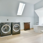 A bathroom with two washing machines and a tub.
