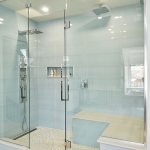 A large glass shower with a bench in the middle